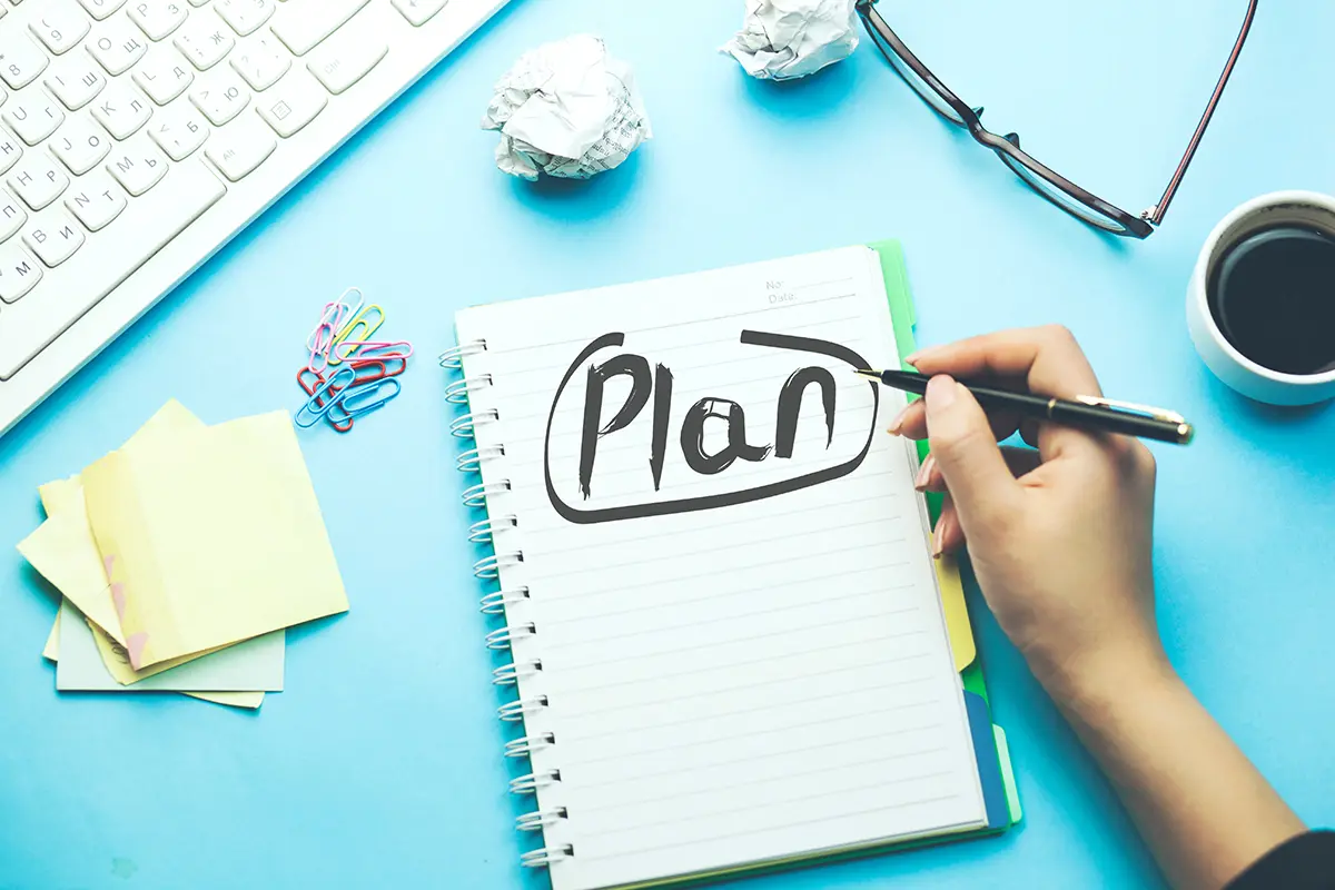 woman written plan on notepad with keyboard and stationary on table