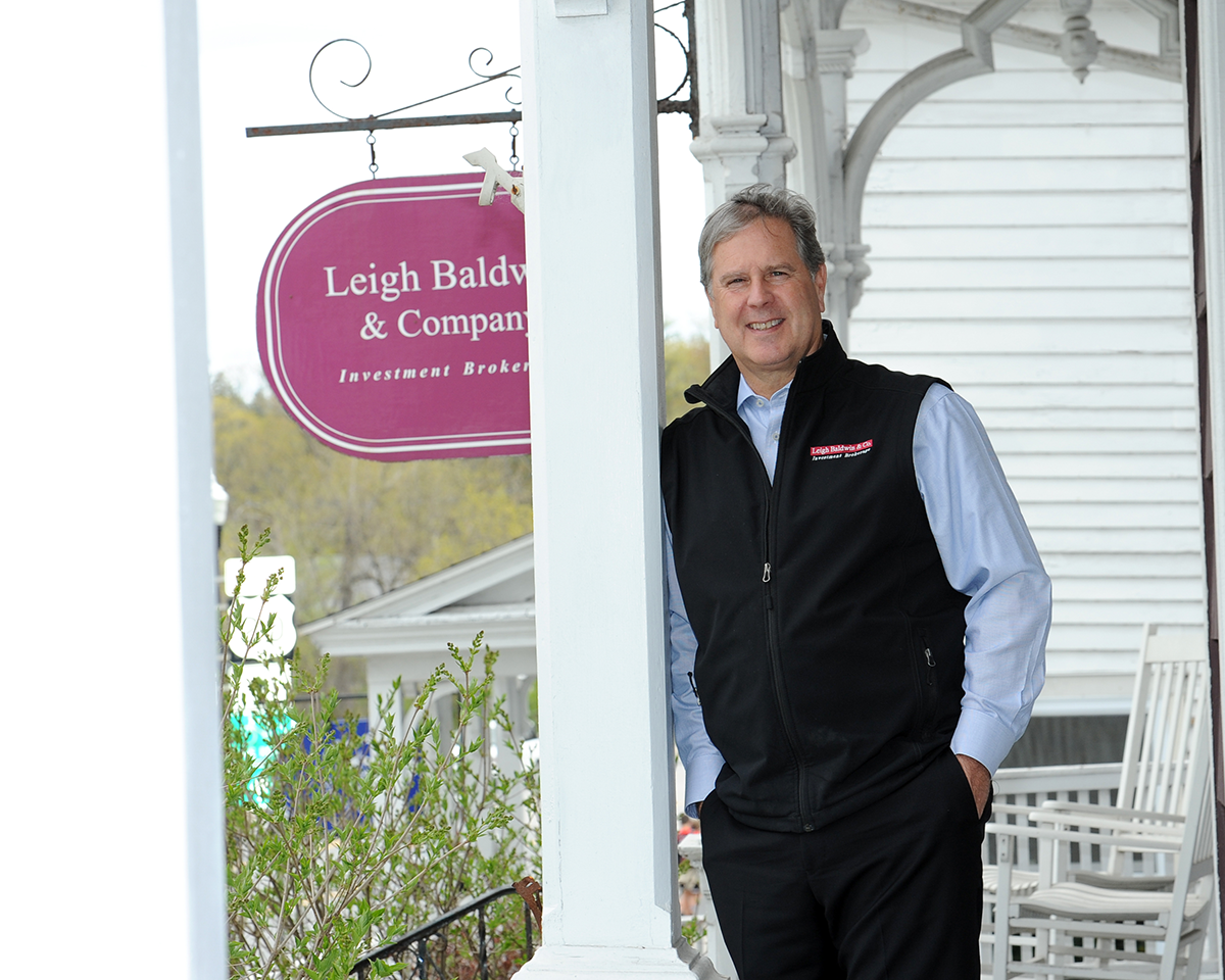 Leigh Baldwin standing on porch of office with Leigh Baldwin & Company sign in background